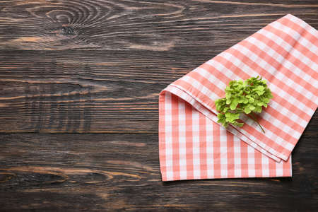 New checkered napkin for picnic and plant on dark wooden background