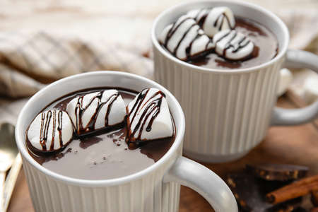 Cups of tasty hot chocolate with marshmallow on table, closeup