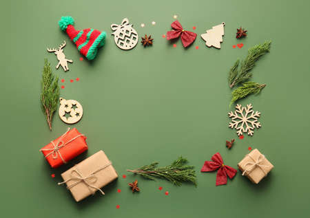 Frame made of coniferous branches, gift boxes and Christmas decorations on color background