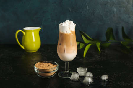 Glass of iced hojicha latte and powder on black background