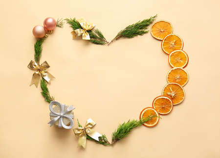 Heart made of coniferous branches, Christmas decorations and dried orange slices on color backgroundの写真素材