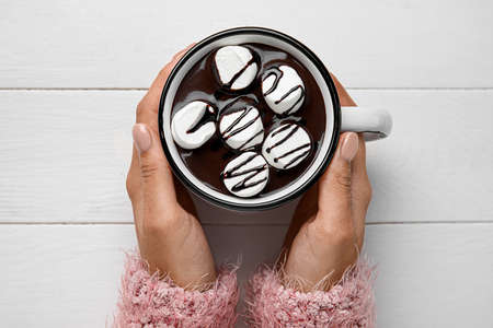 Woman holding cup of tasty hot chocolate with marshmallow on white background