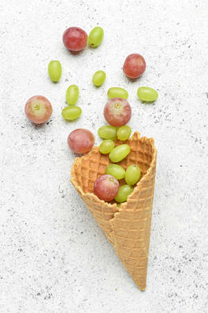 Wafer cone with fresh grapes on light backgroundの写真素材