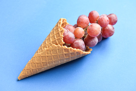 Wafer cone with fresh grapes on color backgroundの写真素材