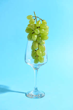 Glass with fresh green grapes on color backgroundの写真素材