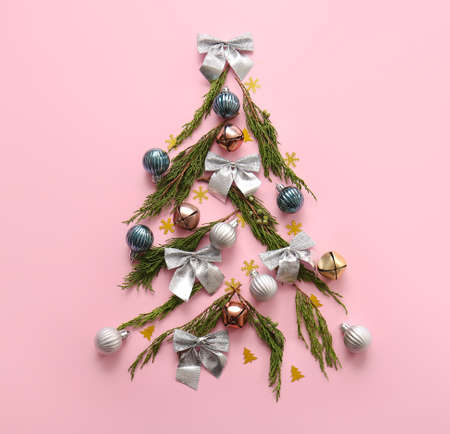 Tree made of coniferous branches and Christmas decor on pink background