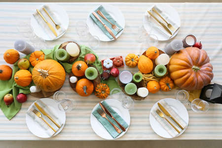 Beautiful table setting with fresh pumpkins and candles in the roomの写真素材