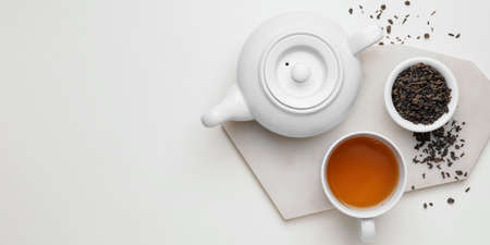 Teapot, cup of tea and dry leaves in bowl on white background with space for textの写真素材