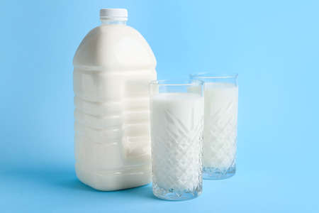 Gallon bottle and glasses of milk on blue backgroundの写真素材