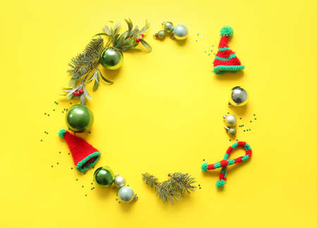 Frame made of Christmas decor and knitted clothes on yellow background