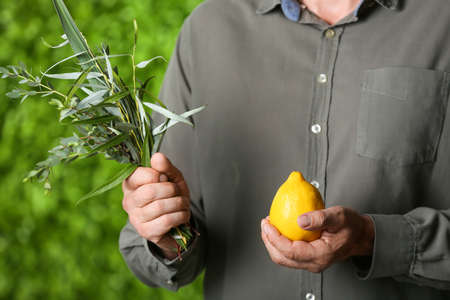 Man holding Sukkot festival symbols on green background, closeup