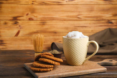 Cup of tasty iced hojicha latte and cookies on wooden tableの写真素材