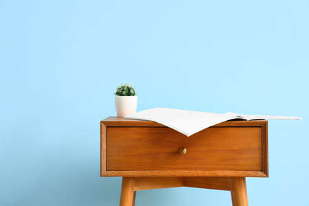 Wooden bedside table with houseplant on blue wall backgroundの写真素材