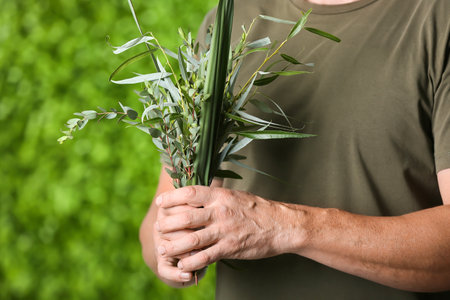 Man holding twigs of Sukkot festival symbols on green background, closeupの写真素材