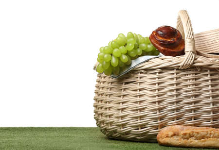 Wicker basket with tasty food for picnic on white backgroundの写真素材