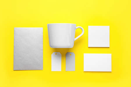 Blank cup, cards and tags on yellow background