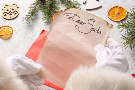 Santa Claus reading wish list letter with text DEAR SANTA on light table, closeupの写真素材