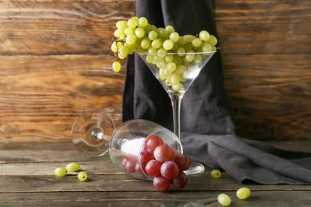 Wine glasses with ripe grapes on wooden backgroundの写真素材