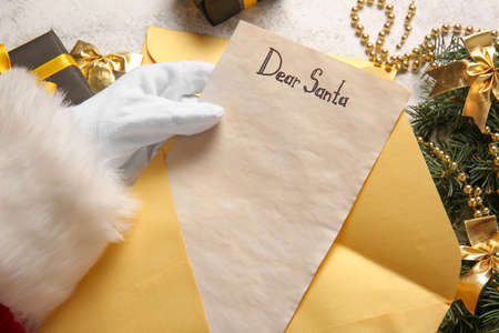 Santa Claus holding envelope and letter with text DEAR SANTA, closeup