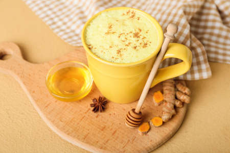 Cup of healthy homemade turmeric latte with star anise and honey on color backgroundの写真素材