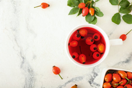 Cup of tasty rose hip tea and berries on white marble backgroundの写真素材