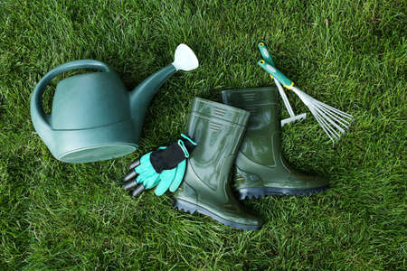 Gardening tools and boots on green grass outdoorsの写真素材