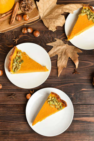 Pieces of delicious pumpkin pie on wooden background