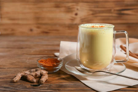 Cup of healthy turmeric latte on wooden tableの写真素材