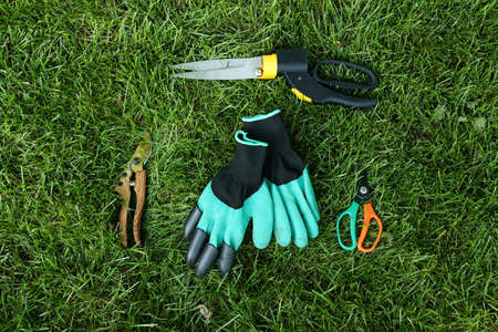 Gardening tools and gloves on green grass outdoorsの写真素材