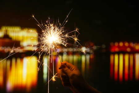 Female hand with beautiful sparkler at night outdoorsの写真素材