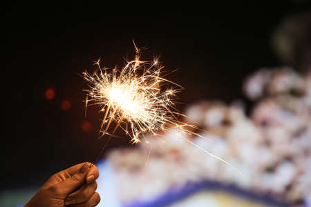 Female hand with beautiful Christmas sparklers at night cityの写真素材