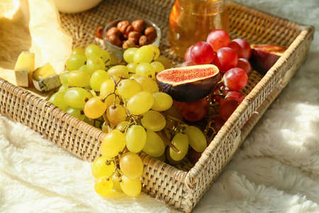 Tray with ripe grapes and snacks on fabric background, closeup