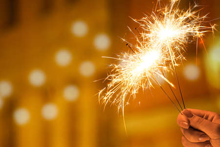 Female hand with beautiful sparklers at night cityの写真素材