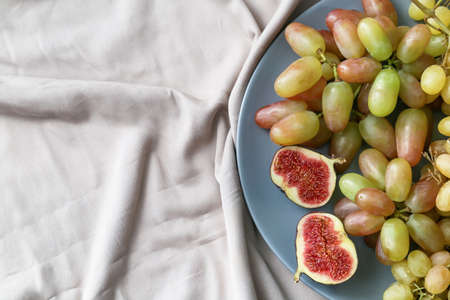 Plate with ripe grapes and fig on fabric background, closeupの写真素材
