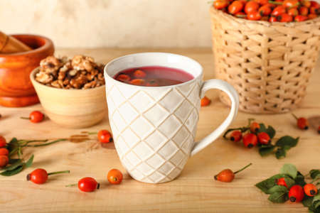 Cup of tasty rose hip tea and berries on tableの写真素材