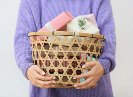 Woman holding basket with Christmas gifts on white background, closeupの写真素材