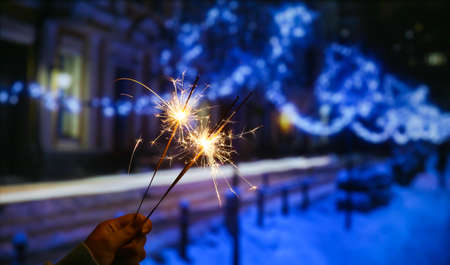 Female hand with beautiful burning sparklers at winter night outdoorsの写真素材
