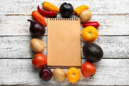 Blank notebook, fresh vegetables and fruits on light wooden background. Vegan Dayの写真素材