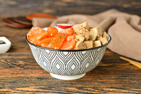 Bowl with tasty rice, salmon and tofu cheese on wooden table, closeupの写真素材