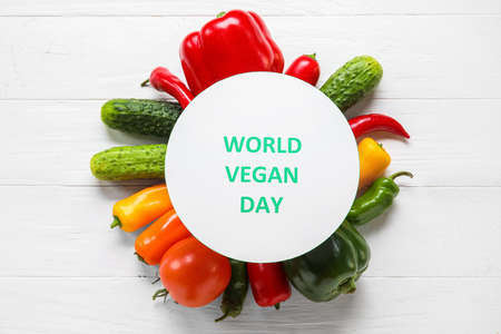 Card with text WORLD VEGAN DAY and vegetables on light wooden backgroundの写真素材