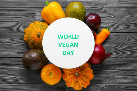 Card with text WORLD VEGAN DAY, fruits and vegetables on dark wooden background
