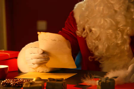 Santa Claus reading letter at table on Christmas eveの写真素材