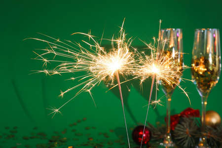 Christmas sparklers, balls and glasses on color backgroundの写真素材