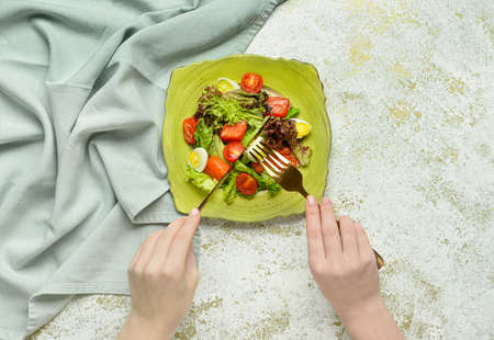 Woman eating fresh salad with salmon and vegetables on white backgroundの写真素材