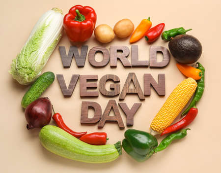 Text WORLD VEGAN DAY made of wooden letters and vegetables on color background