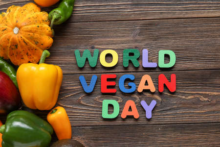 Text WORLD VEGAN DAY made of colorful letters and fresh vegetables on wooden background, closeupの写真素材