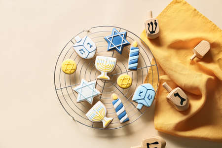 Cooling rack with tasty cookies for Hanukkah celebration and dreidels on light backgroundの写真素材
