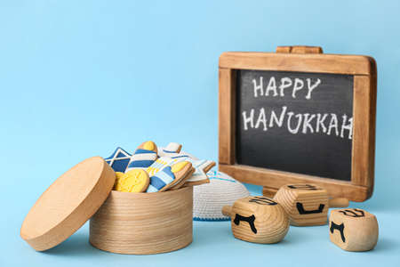 Tasty cookies, dreidels and chalkboard with text HAPPY HANUKKAH on color backgroundの写真素材