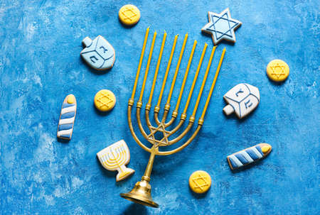 Tasty cookies for Hanukkah celebration with menorah on color backgroundの写真素材