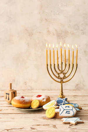 Tasty cookies and donuts for Hanukkah celebration with menorah on tableの写真素材